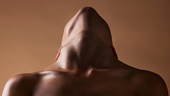 An African-American woman tilting her head back to expose the neck on a  brown background, architectonic and minimalistic feel